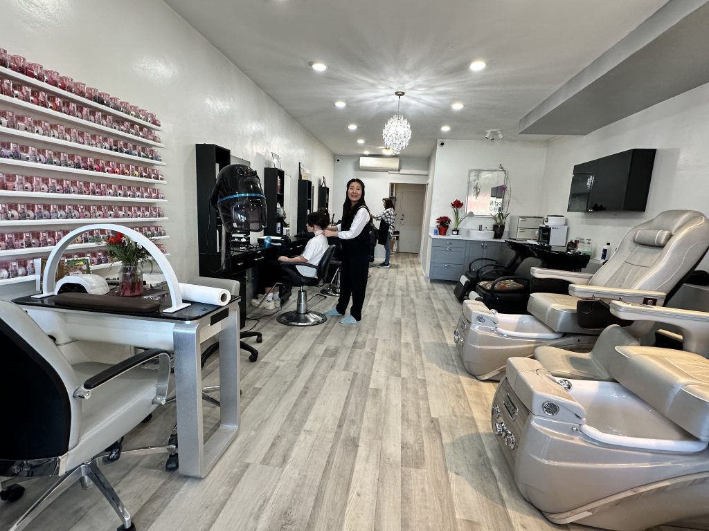 Salon owner welcoming a client inside the renovated Super Nails & Hair studio